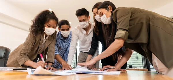 Panorama Interracial asian business team brainstorming idea at office meeting room after reopen due to coronavirus COVID-19. They wear face mask reduce risk to infection as new normal lifestyle.