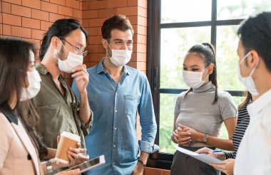 İşçi takımı toplantısı ve yeni bir iş kurmak için beyin fırtınası. Koronavirüs COVID-19 'un yayılmasını önleyen yeni normal bir ofiste koruyucu yüz maskesi takıyorlar..