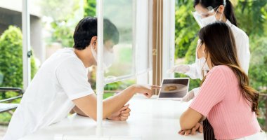 Panorama Asyalı garson restoran elektronik menüsünü göstermek için tablet kullanarak yüz maskesi ve yüz maskesi takıyor ve müşterilere tavsiye veriyor. Yeni normal teknoloji ve yaşam tarzı yemek ve yemek konsepti.