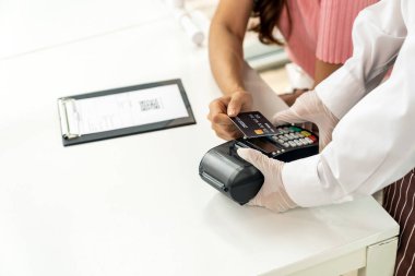 Asyalı kadın müşteriler, dokunmayı azaltmak için yeni bir sosyal mesafe restoranında yedikten sonra kredi kartı ödemeleriyle iletişime geçiyorlar. Çevrimiçi iletişim ve teknoloji kavramı.