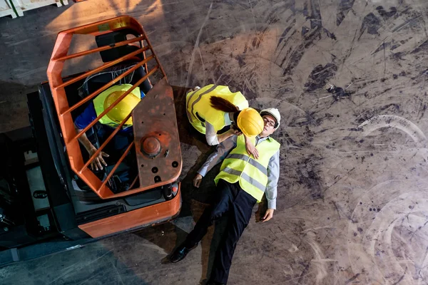 Asian worker Call an ambulance after warehouse manager lying down on warehouse floor after accident from forklift. Using for safety first and business insurance concept. Aerial top view.