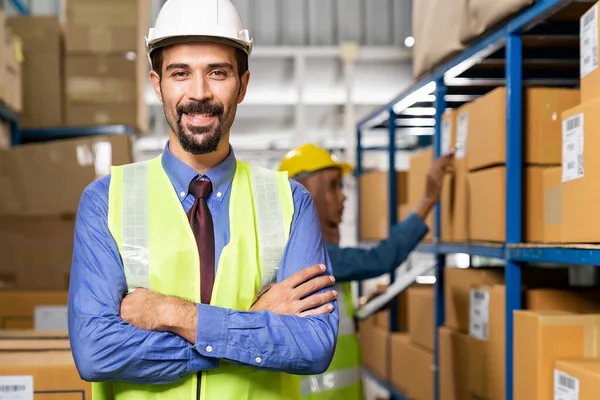Portrait of Middle east Turkish White caucasian warehouse manager crossed arm with his worker working in background in warehouse distribution center environment. Business warehouse inventory concept.