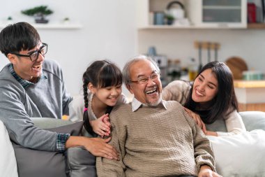 Group Portrait of Happy multigenerational asian family sit on sofa couch in living room with smile. Muti genration family happiness concept. clipart