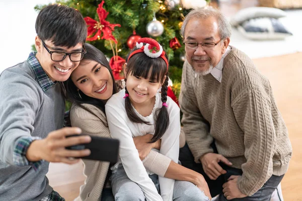 多世代のアジアの家族 お母さんのお父さんの娘の女の子と祖父 クリスマスの飾りを飾る後のクリスマスツリーで自撮りはメリークリスマスとハッピーホリデーの季節の挨拶を準備します — ストック写真