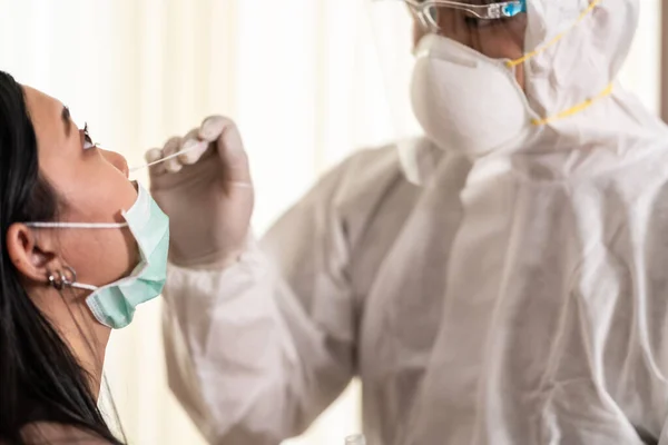 医护人员穿着Ppe西服 在输卵管处用鼻拭子对亚洲妇女进行验尸 Covid 19测试保健概念 — 图库照片