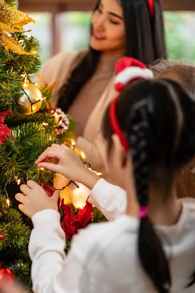 メリークリスマスとハッピーホリデーの季節の挨拶の準備を背景にお母さんとクリスマスツリーを飾る手の小さな女の子を閉じます 世代を超えた家族の関わりと幸福の概念 — ストック写真