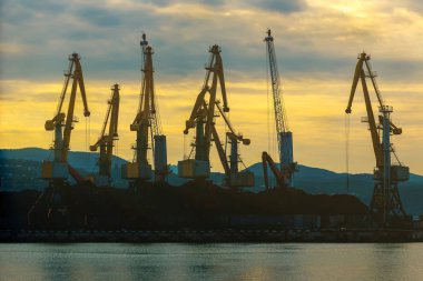 Vinçler bağlantı noktasında şafakta yükleniyor. Çalışma gününün başlangıç denizde