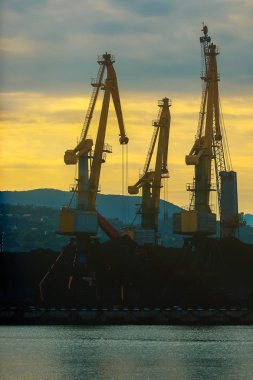 Kargo arka plan üzerinde gündoğumu liman içinde vinç. Şehir ve dağ içinde belgili tanımlık geçmiş