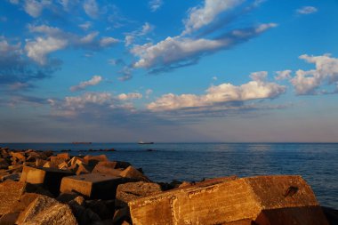 şafak. Balık tutma balıkçı tekneleri denize gidiyor. Ön planda büyük taşlar