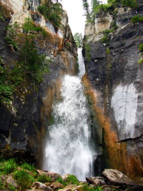 Dağlarda yarıklar arasında güçlü şelale.
