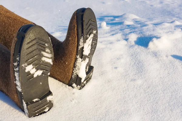 Piernas humanas en zapatos de fieltro caliente en el lado de la nieve. Lugar para copiar información sobre congelación o accidente en el invierno en el frío . — Foto de Stock