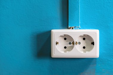 Mavi boyalı duvar üzerinde çift beyaz rozet. Uzay kopyalayın. Topraklama ve kablo kanalı