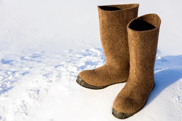 Warm Russian village felt boots of felt with a rubber sole are standing on a snow drift.