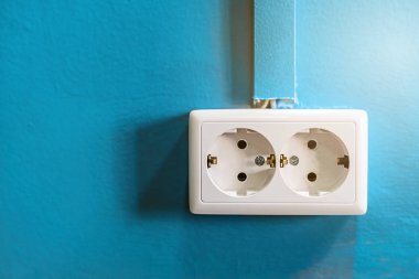 Mavi boyalı duvar üzerinde çift beyaz rozet. Uzay kopyalayın. Topraklama ve kablo kanalı