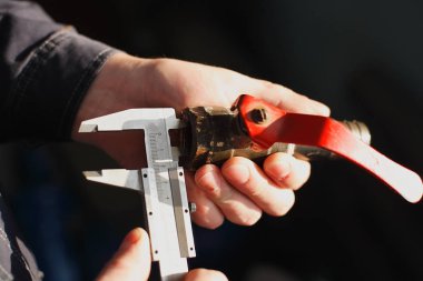 İşçi bir dokunun ve bir kumpas elinde tutuyor. Boru çapı ölçer. Yakın çekim