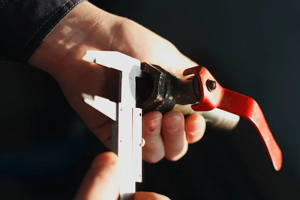 The worker holds in his hand a tap and a caliper. Measures the diameter of the pipe. Close-up