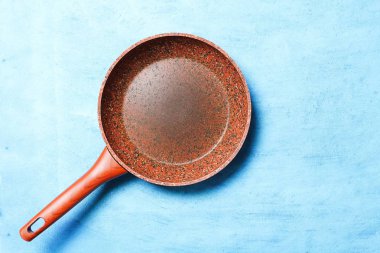 Mavi bir arka plan üzerinde bir taş kaplama ile kızartma tavası. Uzay kopyalayın. Üstten görünüm. Yemekleri yağsız sağlıklı yemekler pişirmek için