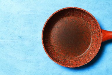 Mavi arka plan üzerinde Granit kaplama ile kızartma tavası. Uzay kopyalayın. Üstten görünüm. Yemekleri yağsız sağlıklı yemekler pişirmek için