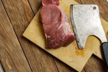 Kesim et için bir balta ve taze sulu biftek kesme tahtası yalan. Üstten görünüm. Et yemekleri yemek pişirmek için arka plan