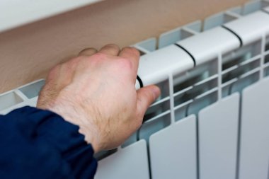 Bir adamın elini bir daire veya office Isıtma batarya sıcaklığını denetler. Soğuk sezon için hazırlık. Yakın çekim