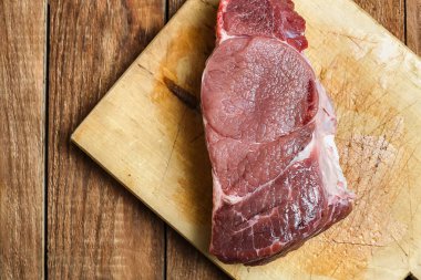 Sulu kanlı Sığır biftek bir Ahşap Doğrama tahtası üzerinde yatıyor. Taze sığır eti yakın çekim iplikler.