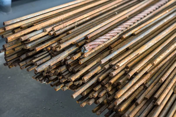 Hastes de metal estão em uma pilha em um piso de concreto no salão de produção . — Fotografia de Stock