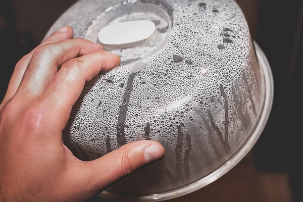 Mano con tapa al vapor para el primer plano de microondas. Condensación y gotas de agua en la superficie del plástico después de calentar los alimentos —  Fotos de Stock