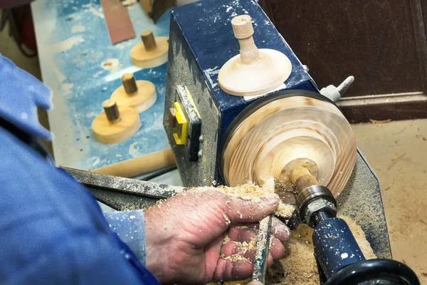 Trabajar carpintero sobre un torno en un árbol. Primer plano de las manos de un hombre con un cincel durante el procesamiento de un espacio en blanco de madera . — Foto de Stock