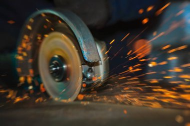 Açı öğütücü disk dönme işlemi sırasında yakın çekim. Alan sığ derinliği ile yapay bulanıklık. Parlak metal kesme kıvılcım