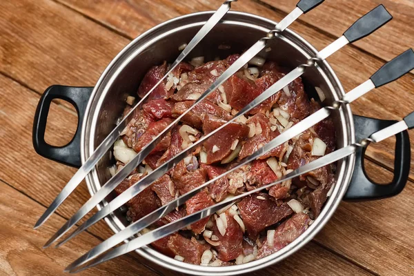 Empty metal skewers lie on the pan with meat for barbecue.  Cooking dishes.  View from above. Beef mixed with onions and spices. — Stock Photo, Image