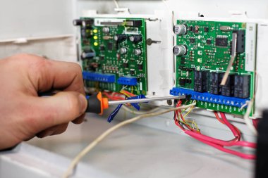 Kontrol ve ölçüm cihazlarındaki mekanik, ekipmanın tamirve ayarını yapar. Tornavida ve güvenlik çipi ile işçinin eli, yakın çekim