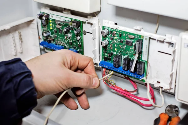 Una mano conecta el cable a la placa de chips. Reparación, mantenimiento y ajuste de equipos por un técnico cualificado — Foto de Stock