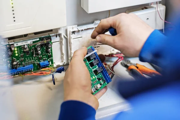 Las manos especializadas conectan el cable al tablero con chips. Reparación, mantenimiento y ajuste de instrumentos y equipos . — Foto de Stock