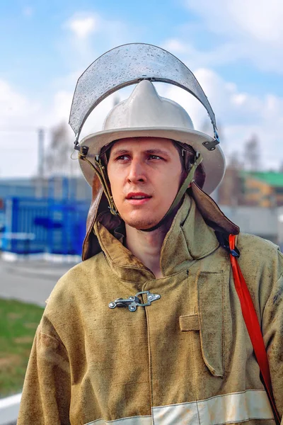 En brandman i skyddskläder och en hjälm ser till sidan. — Stockfoto