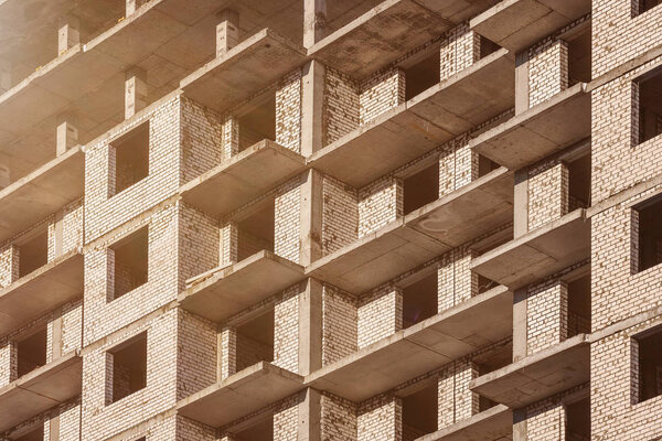 Construction of a new brick house with balconies. Closeup of a wall with sunlight. Delivery of the apartment building.