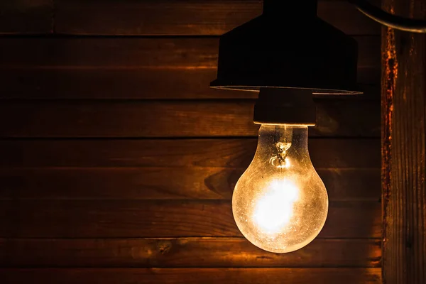 Dirty old incandescent lamp illuminates the grim sooty corner of a dilapidated room