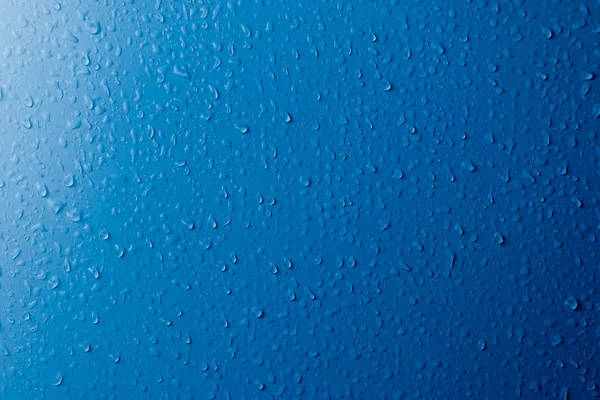 Helder water druppels op een blauw oppervlak. Abstracte achtergrond. — Stockfoto