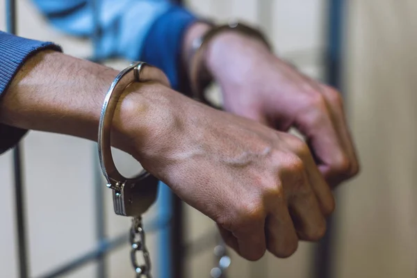 White thin venous hands in handcuffs close-up against the background of the lattice. Punishment for a crime and violation of the law — Stock Photo, Image