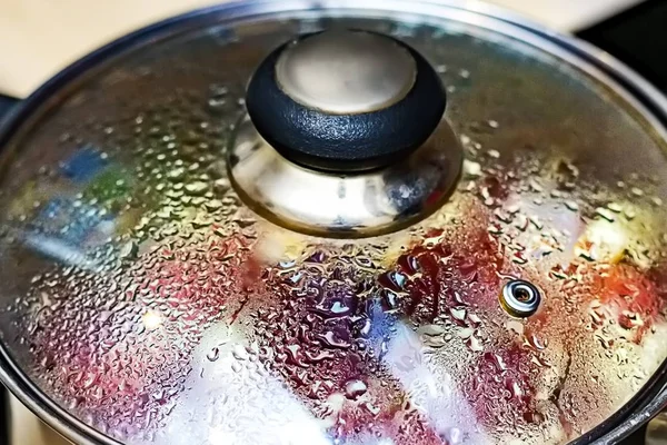 Metal pan with misted lid. Water droplets on the dishes during cooking on the electric stove. Close up. The view from the top. — Stock Photo, Image