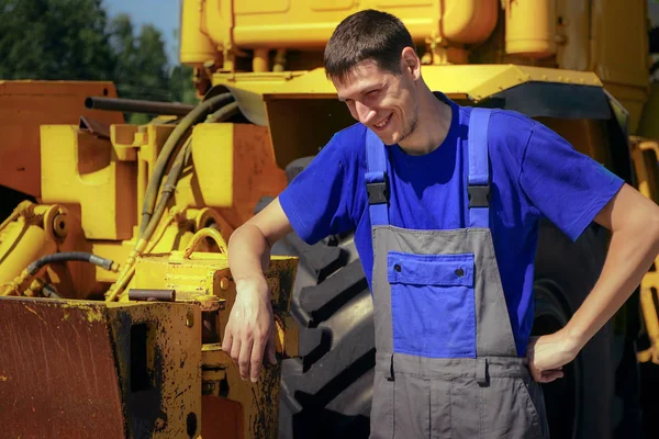 Joven agricultor sonríe en el fondo del tractor . — Foto de Stock