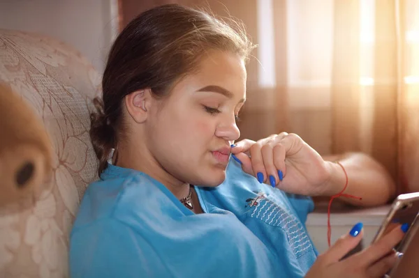 Chica adolescente cuidadosamente mira a la pantalla de un teléfono inteligente —  Fotos de Stock