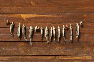 Bir demet kurutulmuş tuzlanmış balık ahşap bir zeminde asılı duruyor. Evde kendi ellerinle bira aperatifleri yapıyorsun.