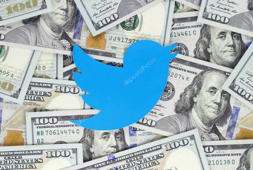 Kiev, Ukraine - September 07, 2018: Twitter bird icon printed on paper, cut and placed on money background. Twitter is an American online news and social networking service