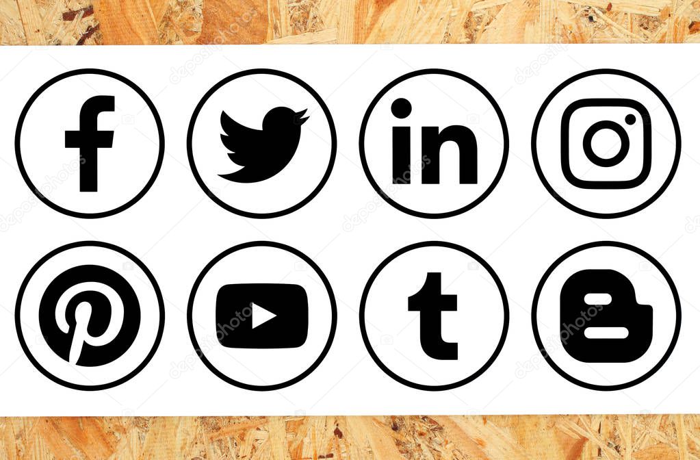 Kiev, Ukraine - November 16, 2018: Collection of popular black circle social media icons with rim printed on paper on wooden background: Facebook, Twitter, Instagram, Pinterest, Blogger and others