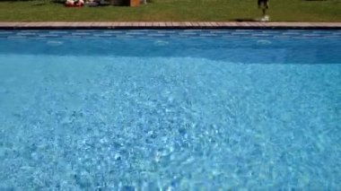 Adam havuzun yanında yürüyor.