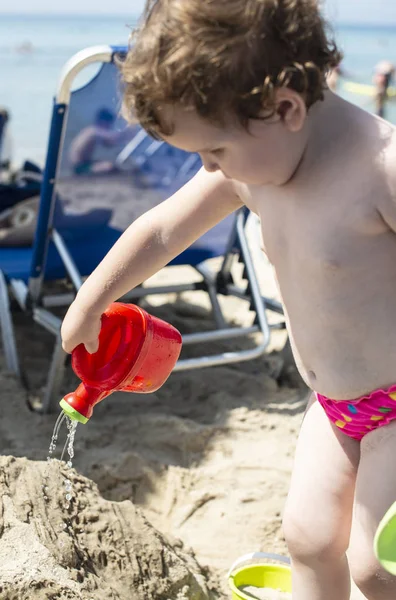 小さな女の子がビーチで水で遊ぶ — ストック写真