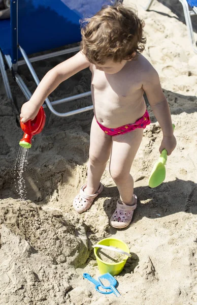 小さな女の子がビーチで水で遊ぶ — ストック写真