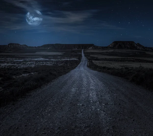 Moon, stars and clouds in the night. Wild west road illuminated from the moon. Moonlight and road background. Dark blue backdrop.