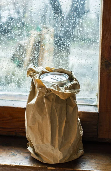 在雨天放在窗户上的棕色包装纸里装满酒精的瓶子 皱巴巴的纸包装 隐藏在纸上的瓶子酒精 隐身饮酒和酗酒的概念 — 图库照片