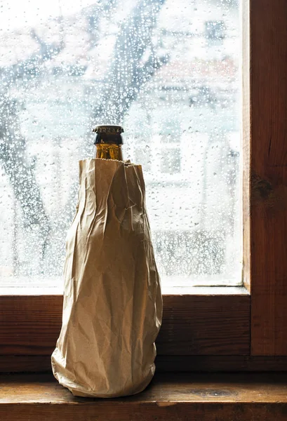酒瓶与酒精在一个棕色的包装纸放置在窗口 — 图库照片